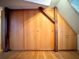 Dieser Schiebetür-Schrank aus Buche als Einbaumöbel unter einer Dachschräge, nutzt den Raum perfekt aus. Drei große Schiebetüren ermöglichen auch auf sehr beengtem Raum übersichtlichen Zugriff auf den Inhalt. Dieser Einbau unter der Dachschräge hat zuvor ungenutzten Raum erschlossen. Die große Schrankfront sorgt für eine klare Aufteilung.
