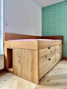 Halbhohes Kinder-Bett aus Massivholz mit viel Stauraum in großen Schubkästen - perfekt für kleine Kinderzimmer und überall dort, wo Stauraum und eine angenehme, erhöhte Liegeebene gewünscht sind.